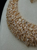 Macro close-up of the collar necklace body showing the dense champagne-toned marquise-cut stone paving in a cascading leaf motif with warm gold-tone setting