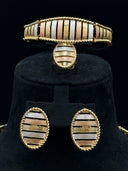 Tri-tone ribbed cuff bracelet, domed ring, and oval stud earrings displayed on a black velvet stand