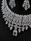 Close-up of the bib necklace body and chandelier earrings showing lavender rectangular halo stones, marquise clear stone separators, and leaf spray drops