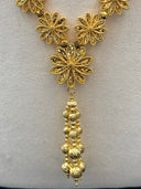 Close-up of the opera necklace tassel drop showing layered ribbed ball pendant and three large filigree flower links at the center front