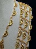 Detail of the long multi-strand half-moon link necklace alongside the crescent bib necklace on a white velvet bust