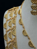 Angled view of the shoulder drape chain draped across a white velvet bust shoulder showing half-moon link construction and daisy spacer detail