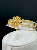 Front view of the full set on a white velvet bust showing the cuff bracelet on top, long tassel drop earrings, and the double-strand clover link necklace