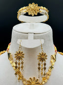 Side view of the long necklace draped on a white velvet bust showing the double-strand clover link chain and a large filigree daisy station with clover tassel drop