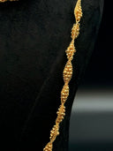 Close-up of the long opera necklace showing the twisted densely clustered faceted bead strands forming repeating diamond-shaped stations with a pinched wave silhouette