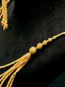 Macro detail of the necklace shoulder gather showing the twisted bead strands converging into the tassel drop with a large twisted ball accent at the junction