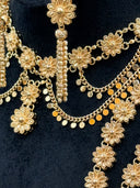 Detail of the collar necklace center showing the filigree daisy station, coiled bar drop, and coin disc fringe on the curb chain