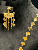 Detail of one chandelier earring showing the starburst stud top, crescent filigree body, and clover and coin tassel drops alongside the clover-link chain