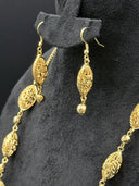 Close-up detail of the earrings alongside the necklace chain, highlighting the lattice oval texture and faceted ball tips