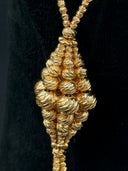 Macro close-up of the diamond-shaped cluster pendant showing graduated engraved spheres with rope-cut texture converging at the center
