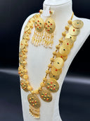Close-up of the pair of oval chandelier earrings showing engraved disc face with scattered red and green stones and teardrop tassel fringe with pearl tips